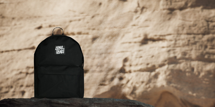 One of our adventure bags, the Longsands "Company Backpack" in black, sat atop a rocky cliff-face - reminiscent of the desert or Dune
